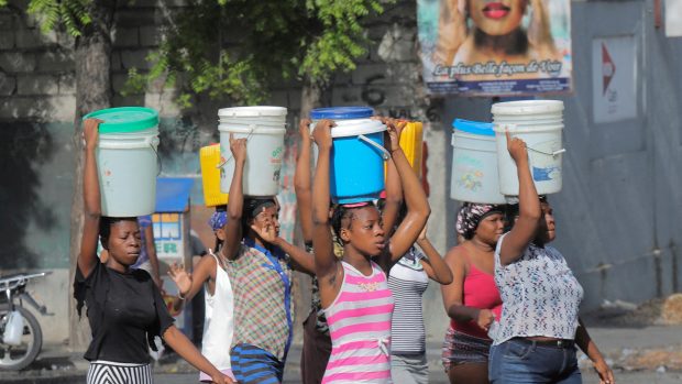 ženy na hlavách nesou vodu při krizi na Haiti