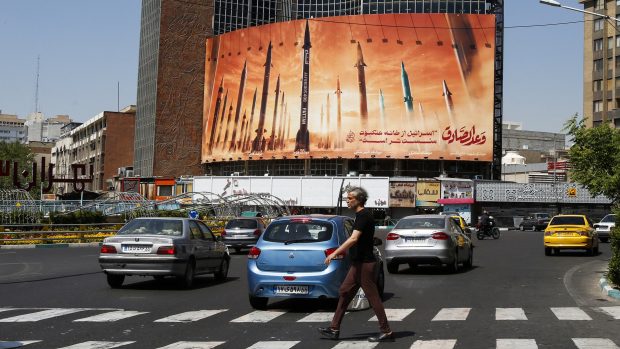 Muž v íránském Teheránu prochází kolem propagandistického plakátu