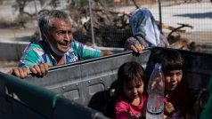 Dva muži tlačí popelnici se svým majetkem a dětmi (foto z 11. září z řeckého ostrova Lesbos)