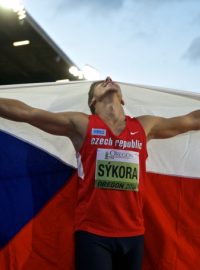 Desetibojař Jiří Sýkora se raduje s českou vlajkou za zády ze zisku zlaté medaile na MS juniorů v Eugene