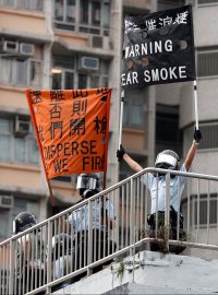 Příslušníci policie drží transparenty s výstrahou před použitím slzného plynu při demonstraci v Hongkongu