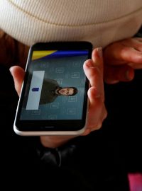 Ukrajinci poslouchají projev prezidenta Volodymyra Zelenského na mobilním telefonu