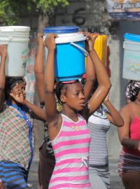 ženy na hlavách nesou vodu při krizi na Haiti