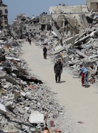 Palestinci prochází kolem ruin budov zničených během izraelské vojenské ofenzívy