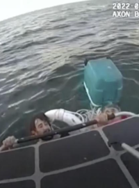 Mladší z dvojice mužů se drží lodi policistů během záchrany.