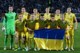 Ukrajinští fotbalisté pózují s vlajkou své země před barážovým utkáním, ve kterém bojovali o postup na Euro