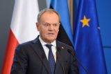 Polský premiér Donald Tusk s polskou, estonskou a unijní vlajkou v pozadí.