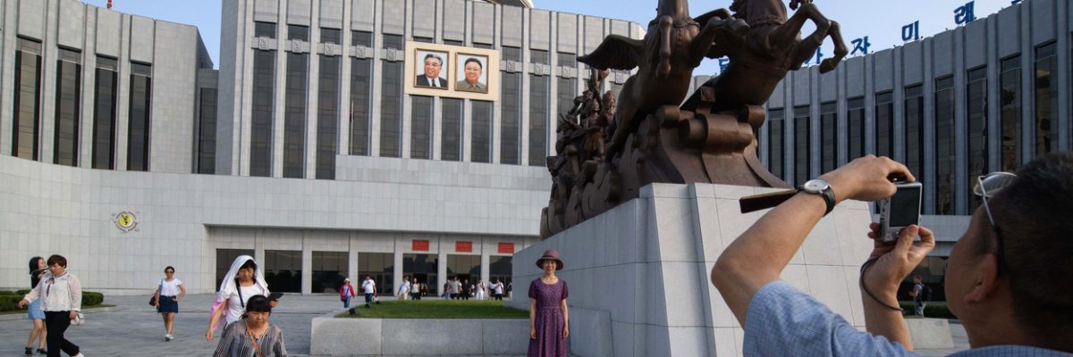 Turisti se fotí v Pchjongjangu před Palácem školáků Mangjongde, 26. července 2018.