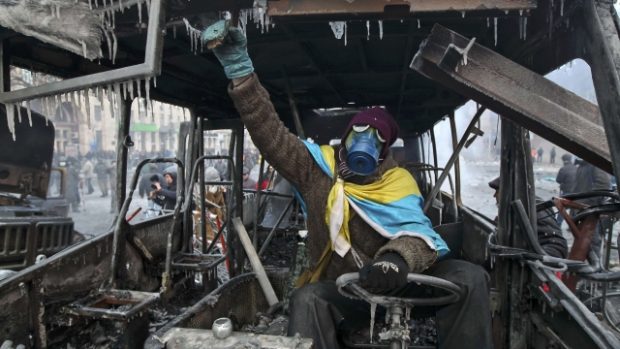 Ukrajina, Kyjev. Proevropský demonstrant ve shořelých troskách policejního autobusu