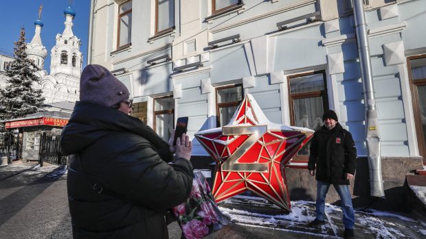 Muž v centru Moskvy vedle instalace rudé hvězdy s písmenem „Z“