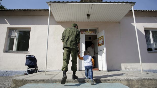 Muž vede syna první školní den do školy v Doněcku. Archivní snímek z roku 2015.