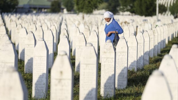 Žena truchlí za oběti srebrenického masakru uprostřed dlouhé řady náhrobků v patmátníku Srebrenica-Potočari