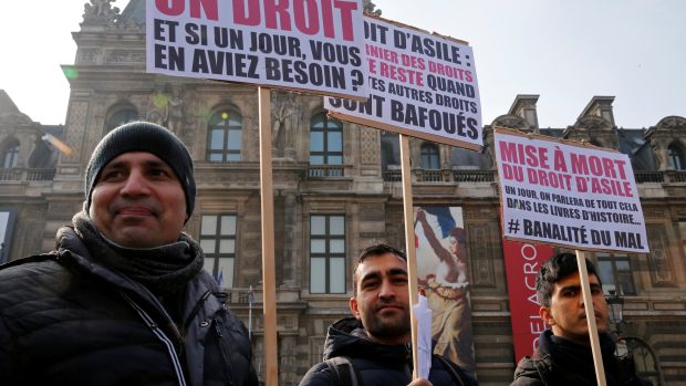 Protest proti novému francouzskému zákonu o azylu. Demonstranti drží plakáty s nápisy jako „Azyl je právo“