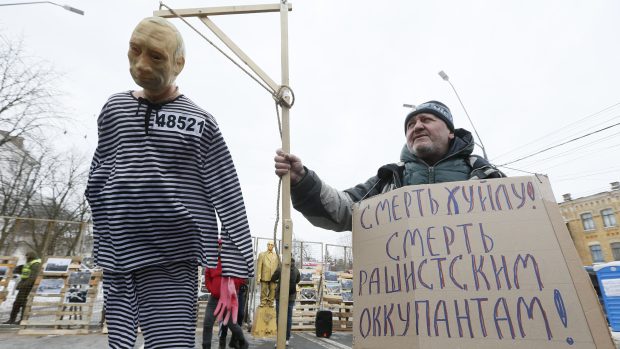 Účastník demonstrace ukrajinských nacionalistů před ruskou ambasádou v Kyjevě drží oběšence s tváří prezidenta Putina