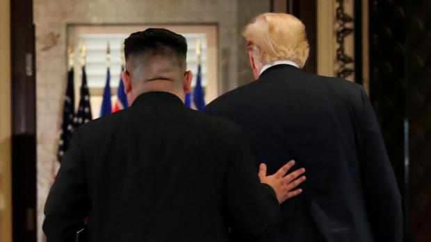 Donald Trump a Kim Čong-un odchází z místnosti po podpisu dokumentu.