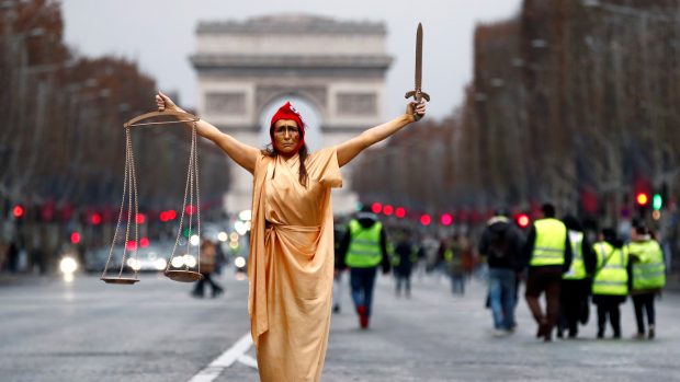 Žena v převleku za Spravedlnost a za jeden ze symbolů Francouzské republiky Marianne pózuje během protestů „žlutých vest“ poblíž Vítězného oblouku.