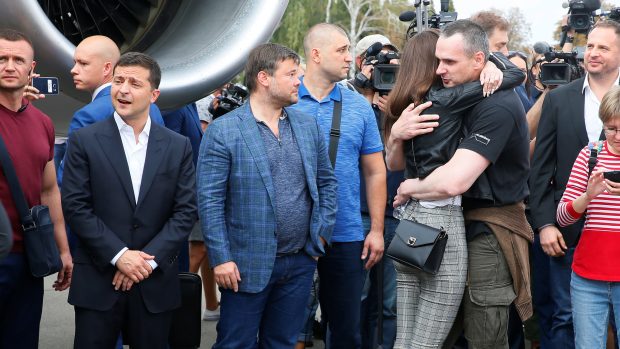 Ukrajinský prezident Volodomyr Zelenskyj (vlevo) přihlíží návratu vězňů z Ruska. Mezi nimi přiletěl i režisér Oleg Sencov (uprostřed).