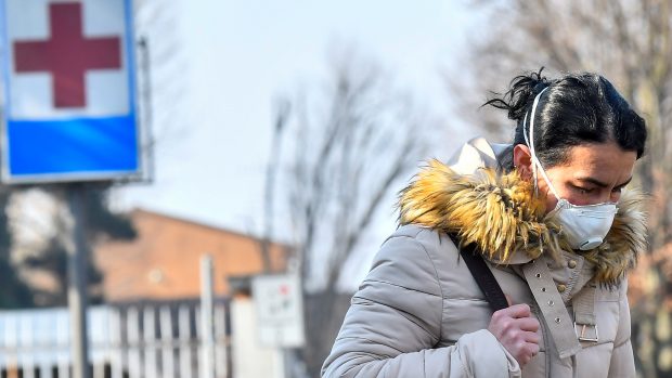 Žena s obličejovou maskou opuští nemocnici v italském městě Codogne.