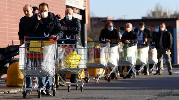 Lidé v ochranných rouškách opouští obchod ve městě Pioltello nedaleko Milána.