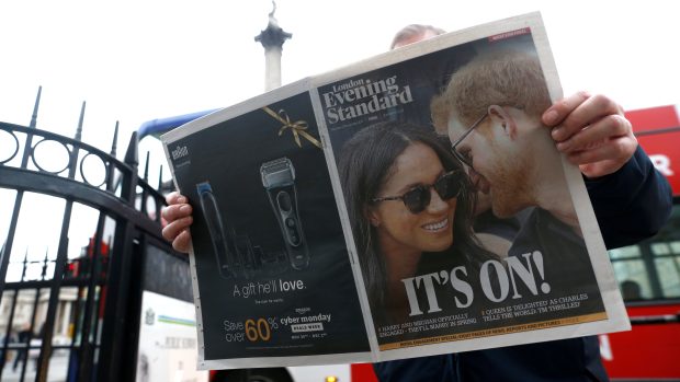 Muž si čte londýnský večerník London Evening Standard. Na jeho titulce jsou Meghan Markleová a její muž princ Harry