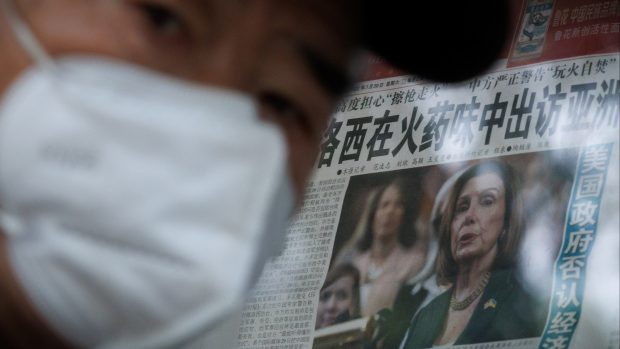 Muž v Pekingu u novinového stánku, ve kterém noviny informují o cestě americké předsedkyně sněmovny Nancy Pelosiové