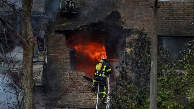 Hasič zasahující při požáru domu, který zasáhla raketa během útoku na Kyjev