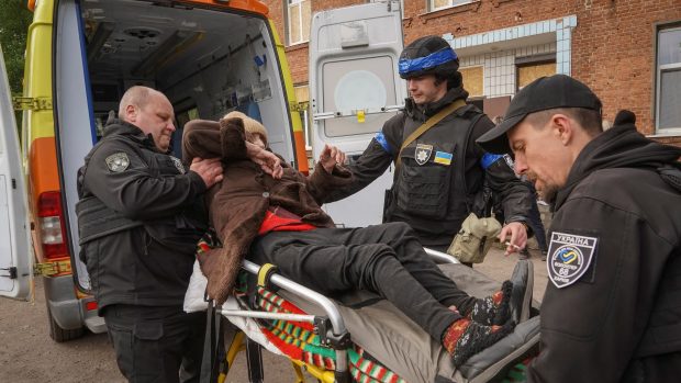 Policisté pomáhají místnímu obyvateli při evakuaci do Charkova kvůli ruskému ostřelování u města Vovčansk