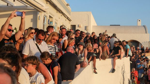 Turisté pozorující západ slunce na ostrově Santorini