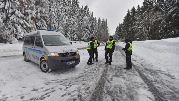 Policisté hlídkují u abertamské křižovatky nad Jáchymovem, kde silničáři uzavřeli sněhem zavátou silnici směrem na Boží Dar