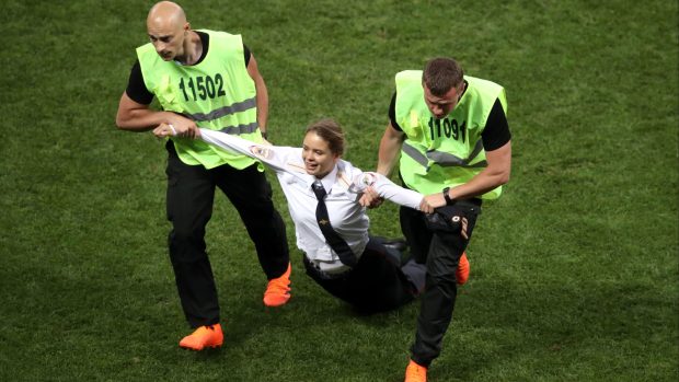 Členku Pussy Riot odvádějí z hřiště, na které vyběhla během finále fotbalového šampionátu