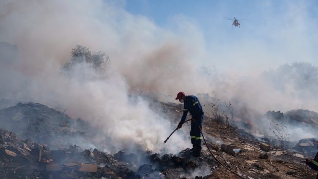 Hasič se snaží uhasit požár na předměstí Koropi ve východní části Atén