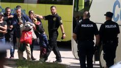 Uprchlíci za dohledu bosenské policie vycházejí z autobusu v uprchlickém centru v Salakovci poblíž Mostaru (18. května 2018).