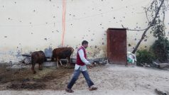 Muž prochází kolem prostřílené fasády domu ve vesnici na pákistánské straně hranice