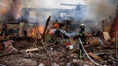 Hasič v ruinách hořící budovy zničené raketovým útokem poblíž letiště v Charkově