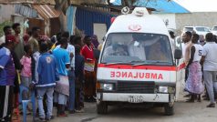 Lidé shromaždění okolo sanitky, která převáží tělo neidentifikované ženy zabité při explozi na pláži Lido v Mogadišu