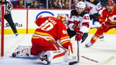 Brankář Calgary Flames Daniel Vladař zasahuje proti Lukeu Hughesovi z New Jersey Devils