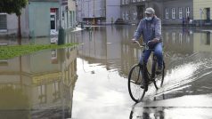 Cyklista projíždí zaplavenou ulicí v Brodku u Přerova, kde se po intenzivních deštích vylila z břehů říčka Olešnice. Fotografie z 15. října