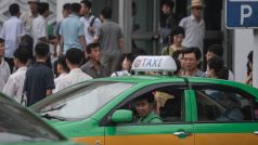 Taxikář vyhlíží z okna svého auta během čekání na zákazníky před hlavním nádraží v Pchjongjangu, červenec 2016.