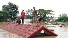 Zaplaveni: vodou uvěznění vesničané čekají na střeše zatopeného domu na evakuaci.