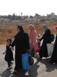 Palestinky procházejí kolem židovské osady v arabském Hebronu. Jejich muži tam možná pracují.