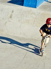 Dětské skatování s koloběžkou ve Strašnickém betonovém skateparku Parku Gutovka