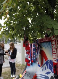 Ženy zapalují svíčky před hokejovým stadionem v Jaroslavli.