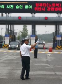 Auta se zaměstnanci Kesongu projíždí skrz bránu ve městě Paju jižně od korejské demilitarizované zóny