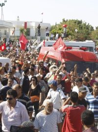 Lidé jdou podél ambulance, která veze tělo opozičního politika Muhamada Brahmího