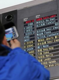 Muž na pekingském letišti si fotí informační tabuli s přílety, malajsijské letadlo tam mělo přistát už před půlnocí SEČ