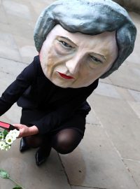Někteří už mají o osudu &quot;tvrdého brexitu&quot; jasno - neprojde. Demonstrantka proti Therese Mayové s maskou britské premiérky na hlavě pokládá květiny k symbolickému náhrobku před Downing Street. Povolební pátek, Londýn.