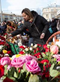 Obyvatelé u zdi obchodního centra, kde vznikl improvizovaný památník, vedle květin kladou také hračky.