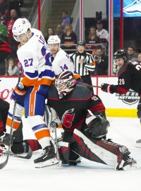 Gólman Caroliny Hurricanes Curtis McElhinney si snaží najít prostor, aby viděl na puk ve třetím zápase druhého kola play-off NHL proti New Yorku Islanders