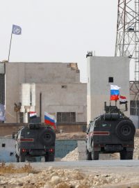 Ruské a syrské vlajky vlají na vojenských autech poblíž města Manbidž
