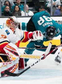 Obránce San Jose Brent Burns padá při souboji s českým brankářem Davidem Rittichem z Calgary Flames